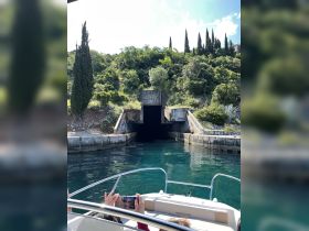 Guests aboard a boat capture the moment as they approach a mysterious tunnel surrounded by lush greenery — a perfect scene for adventure seekers exploring hidden gems.