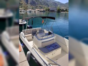 A clean and spacious interior view of a boat, showcasing the seating and helm area, perfect for comfortable cruising on the water.