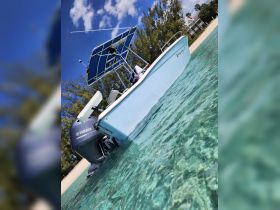 A stunning side view of a boat named 'Easy Drift' anchored in crystal-clear waters, showcasing its sleek design and vibrant blue canopy against a picturesque backdrop.