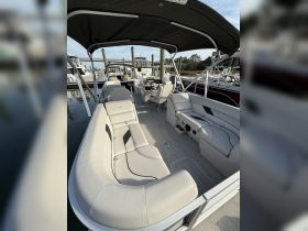 A spacious interior view of a pontoon boat featuring comfortable seating and a helm, perfect for relaxing on the water.
