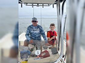 A father and son enjoy a fishing trip together on a boat, creating lasting memories on the water. Perfect for family bonding and outdoor adventures.