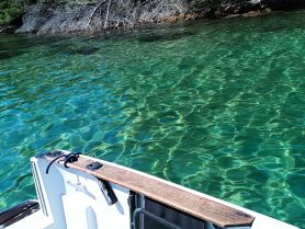 A serene view of a boat's edge with crystal-clear turquoise waters, showcasing the beauty of the surrounding nature.