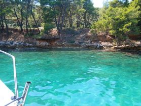 A serene view of turquoise waters and a rocky shoreline, captured from the bow of a boat, showcasing the beauty of nature and ideal for peaceful boating excursions.