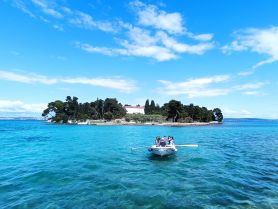 A group enjoys a scenic boat ride near a picturesque island, surrounded by stunning turquoise waters — a perfect getaway for adventure seekers.