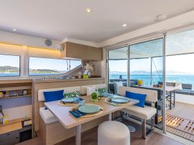 A beautifully designed interior of a yacht featuring a cozy dining area with stunning views of the water, perfect for enjoying meals while cruising.