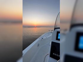 A serene view of a boat's deck at sunset, showcasing the tranquil waters and vibrant sky — perfect for evening cruises.