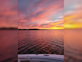 A stunning sunset view over calm waters, captured from the deck of a boat, creating a serene atmosphere perfect for evening cruises.