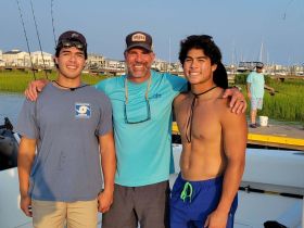 A joyful group of fishermen poses for a photo by the water, capturing a memorable day of fishing and family bonding.