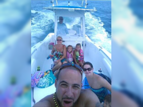 A joyful family enjoys a boat ride, capturing fun moments together with kids in life jackets — perfect for family outings on the water.