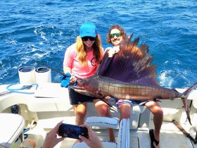 A couple proudly displays their catch of the day, a magnificent sailfish, while enjoying a fishing adventure on the open water.