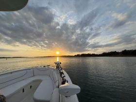 A serene sunset view from the deck of a boat, showcasing the tranquil waters and beautiful sky — perfect for evening cruises.