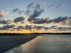A stunning sunset over a serene beach, showcasing the tranquil beauty of the coastline — perfect for evening boat trips or romantic getaways.