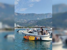 A group enjoys a sunny day aboard a boat, with a paddleboard ready for fun in the water — perfect for summer adventures and social outings.