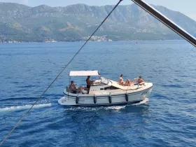 A lively group enjoys a sunny day on a boat, perfect for relaxation and on-water activities amidst stunning coastal scenery.