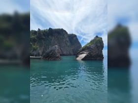 Breathtaking view of unique rock formations along a serene coastline, surrounded by crystal-clear turquoise waters — a perfect destination for nature lovers and boat tours.