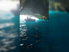 A boat navigates through a stunning cave, showcasing the vibrant blue waters and the thrill of exploration — perfect for adventure seekers.