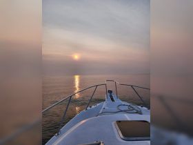 A serene view from the front of a boat at sunset, reflecting golden hues on calm waters — perfect for peaceful evening cruises.