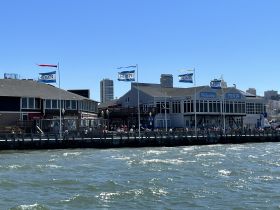 A view of Pier 39 with buildings and flags, capturing the vibrant atmosphere of a popular waterfront destination.