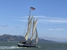 A majestic sailing ship navigates the waters with its sails fully unfurled, showcasing a perfect day for sailing amidst stunning coastal scenery.