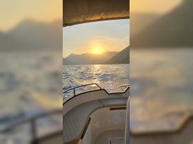 A stunning sunset view from the deck of a boat, showcasing the serene waters and mountainous backdrop — perfect for evening cruises.
