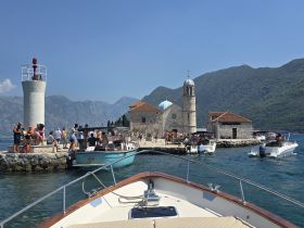 A vibrant scene at a picturesque island with a historic church, showcasing a lively group of visitors enjoying the beautiful coastline and clear waters.