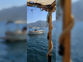 A scenic view of a boat named 'Barbados' docked in calm waters, framed by a picturesque mountain backdrop — perfect for exploring the beauty of the coastline.