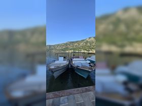 Two boats docked at a serene waterfront, surrounded by stunning mountainous scenery — perfect for a day of exploration on the water.