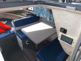 Interior view of a boat cabin featuring comfortable seating and a table, ideal for relaxing or dining while on the water.