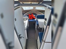 The interior of a boat featuring a cozy seating area and helm, perfect for relaxing and navigating on the water.