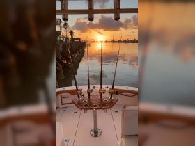 A serene view of fishing rods set up on a boat as the sun sets over the water, perfect for a relaxing day of fishing.