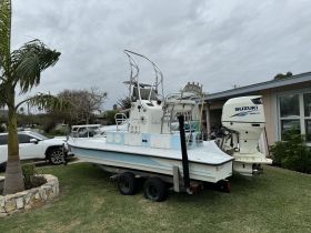 A sleek speedboat is parked on a trailer in a residential area, showcasing its design and features, perfect for fishing or leisure outings.