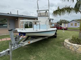 A center console boat on a trailer in front of a house, showcasing its structure and design, perfect for fishing or leisure outings.