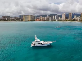 A stunning aerial view of a yacht cruising through crystal-clear waters, with a vibrant city skyline in the background, perfect for showcasing luxury boating experiences.