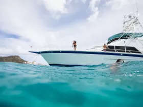 A group enjoys a fun day on the water, with one person swimming and others on the deck of the boat 'Ina Kai' — perfect for summer adventures and ocean exploration.