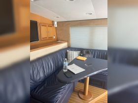 Interior view of a cozy boat cabin featuring comfortable seating and a table, perfect for relaxing or dining while on the water.