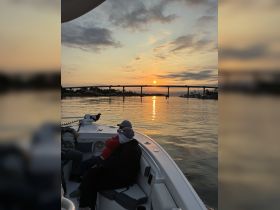 Two guests enjoy a serene sunset view from the deck of a boat, creating a perfect atmosphere for relaxation and memorable moments on the water.