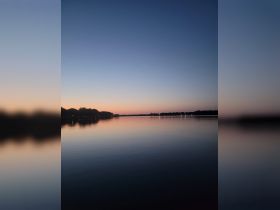 A serene twilight scene over calm waters, capturing the transition from day to night.