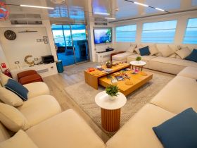 A spacious and modern lounge area inside a boat, featuring comfortable seating and a cozy atmosphere, perfect for relaxing during a cruise.