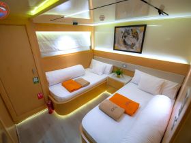 A cozy interior view of a boat cabin featuring two beds, neatly arranged towels, and modern decor, perfect for comfortable overnight stays on the water.