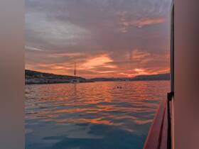 A serene sunset view over calm waters, featuring a sailboat silhouetted against the vibrant sky — perfect for capturing the beauty of evening boat rides.