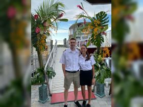 Two crew members pose in front of a beautifully decorated boat entrance, ready to welcome guests for an exciting day on the water.