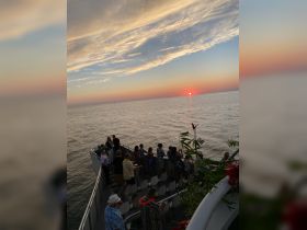 A lively group enjoys a stunning sunset aboard a boat, creating a perfect backdrop for memorable celebrations on the water.