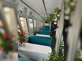 The interior of a boat features elegantly set tables with floral arrangements, creating a welcoming dining atmosphere for guests. Ideal for private events or dining experiences on the water.