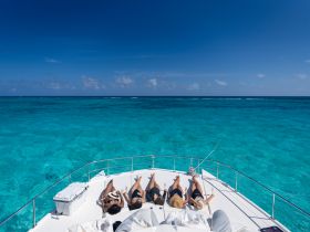 A group of friends relaxes on the deck of a yacht, enjoying cocktails and the stunning turquoise waters — a perfect setting for a luxurious day on the water.