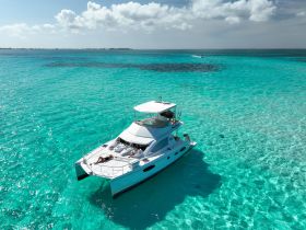A stunning aerial view of a catamaran cruising through crystal-clear turquoise waters, perfect for relaxing and enjoying the beauty of the ocean.