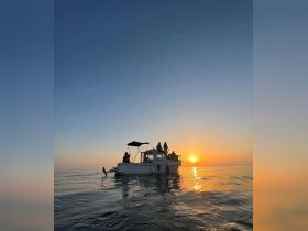 A group enjoys a stunning sunset aboard a boat, creating a perfect backdrop for memorable moments on the water.