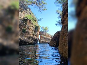 A stunning view of a natural rock formation arching over tranquil waters, perfect for exploring coastal landscapes by boat.