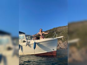 A woman enjoys the sun on the deck of a boat, capturing the essence of a perfect day on the water. Ideal for showcasing fun and relaxation during a boating adventure.
