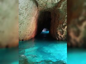 A stunning view of a cave entrance with crystal-clear turquoise water, perfect for exploring hidden gems during a boating adventure.