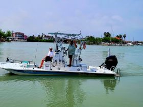 Two individuals enjoy a day on the water aboard a fishing boat, showcasing a perfect blend of relaxation and adventure in a scenic setting.